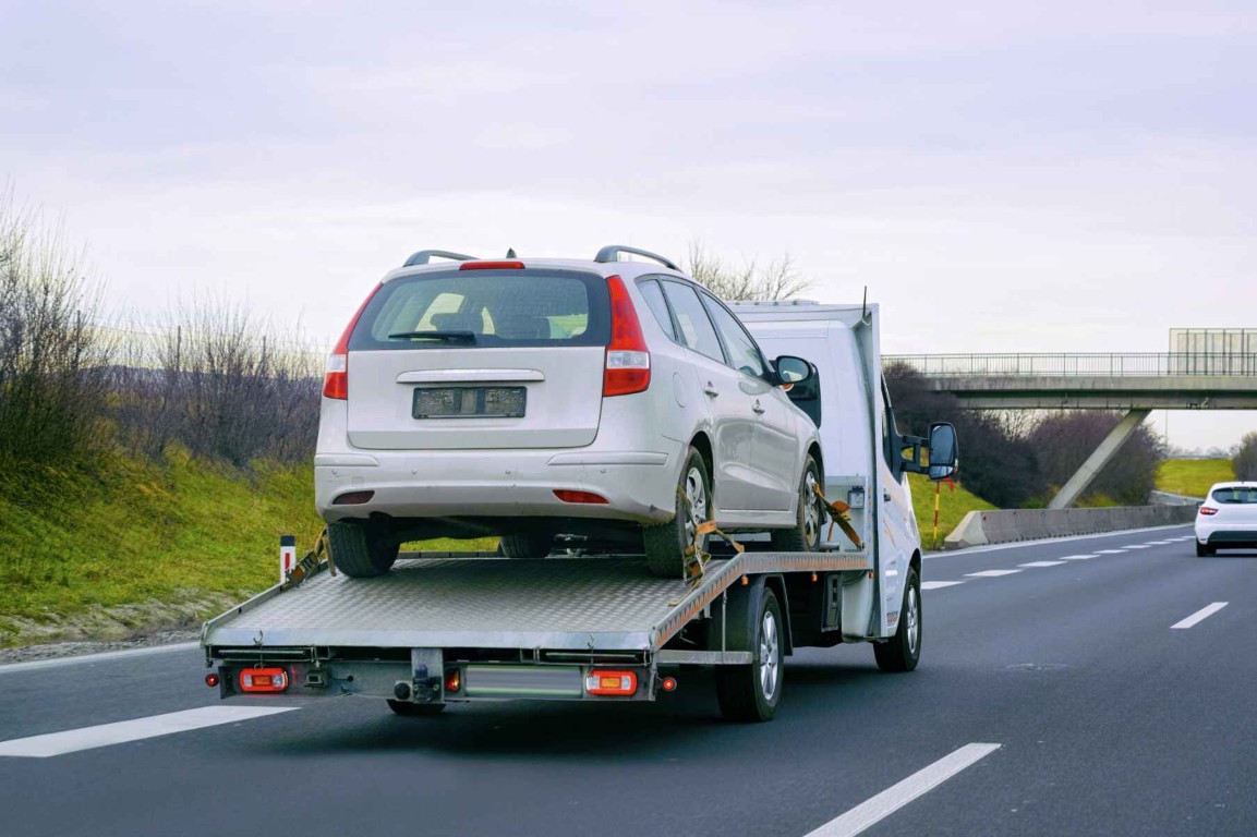 Flatbed tow truck carrying a white SUV on the highway near Copiague, NY
